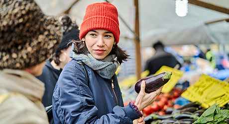 Frau mit roter Mütze hält auf dem Markt eine Aubergine in der Hand | Sparkasse Hannover