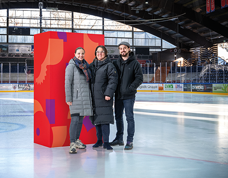 Zwei Frauen und ein Mann stehen auf einer Eisfläche vor einer roten Stele | Sparkasse Hannover