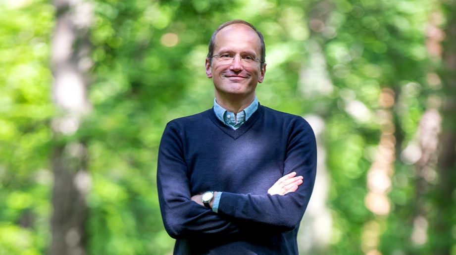 Volker Alt, Vortandsvorsitzender der Sparkasse Hannover lächelt vor einem Wald stehend, mit verschränkten Armen in die Kamera | Sparkasse Hannover