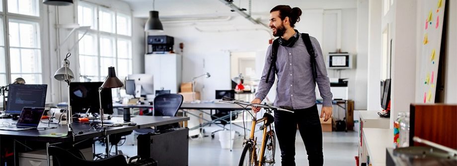 Junge Leute: Berufseinsteiger - Junger Mann mit einem Fahrrad in einem Büro | Sparkasse Hannover