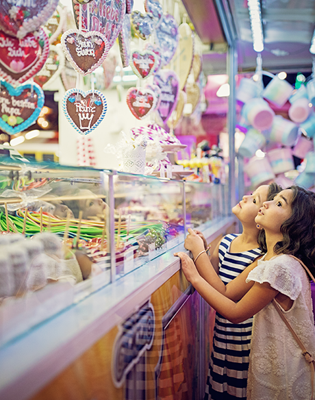 Junge Leute: Zwei kleine Mädchen stehen vor einem Süßigkeitenstand und schauen nach oben | Sparkasse Hannover