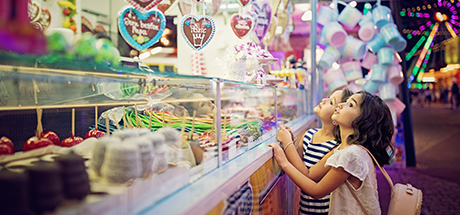 Junge Leute: Zwei kleine Mädchen stehen vor einem Süßigkeitenstand und schauen nach oben | Sparkasse Hannover