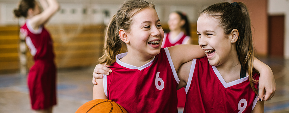 Engagement: Zwei Mädchen stehen lachend nebeneinander im Sportunterricht | Sparkasse Hannover
