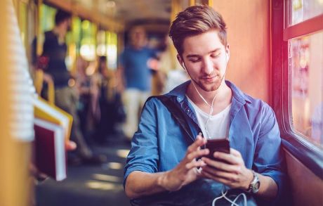 Junge Leute: Onlinewelt – Junger Mann mit einem Smartphone in der Bahn | Sparkasse Hannover