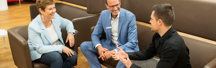 Drei Mitarbeitende der Sparkasse sitzen im Gespräch beisammen.| Sparkasse Hannover