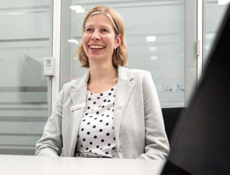 Eine junge Frau sitzt lächelnd an einem Schreibtisch | Sparkasse Hannover