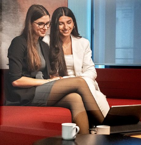 Zwei junge Frauen sitzen auf einem Sofa und lächeln | Sparkasse Hannover