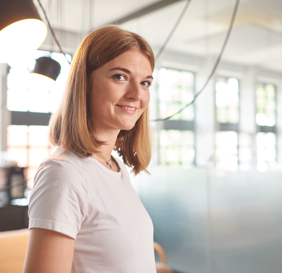  Junge Frau im Bürokontext lächelt freundlich Richtung Betrachtende | Sparkasse Hannover