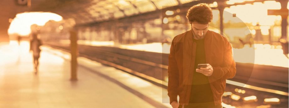 Mann steht am Gleis und schaut auf sein Smartphone | Sparkasse Hannover