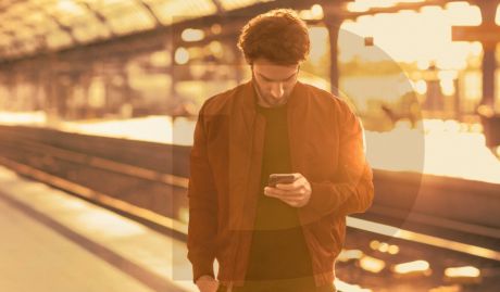 Mann steht am Gleis und schaut auf sein Smartphone | Sparkasse Hannover