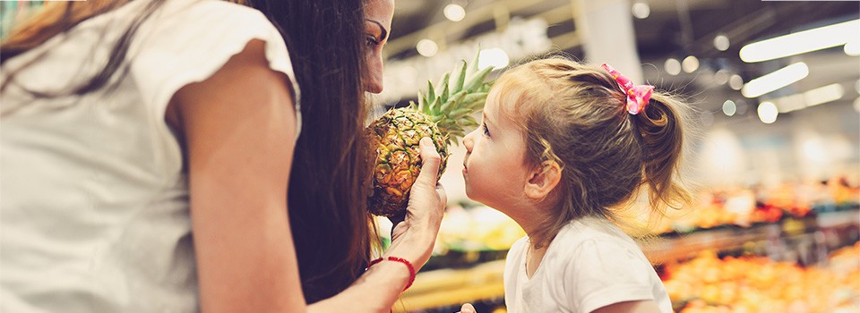 Junge Leute: Kleinkinder - Mädchen schaut Frau mit Ananas in der Hand an | Sparkasse Hannover