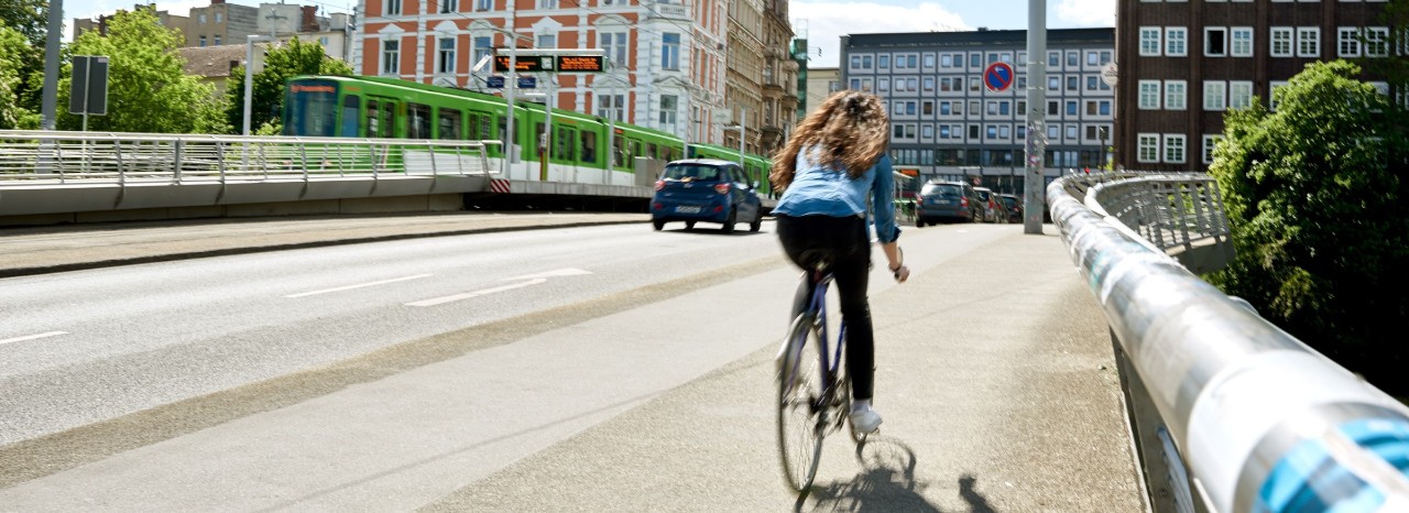 Junge Leute: Frau auf Fahrrad fährt über Benno-Ohnesorg-Brücke  in Hannover| Sparkasse Hannover