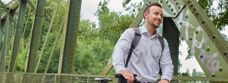 Junger Mann mit Fahrrad auf einer Brücke | Sparkasse Hannover