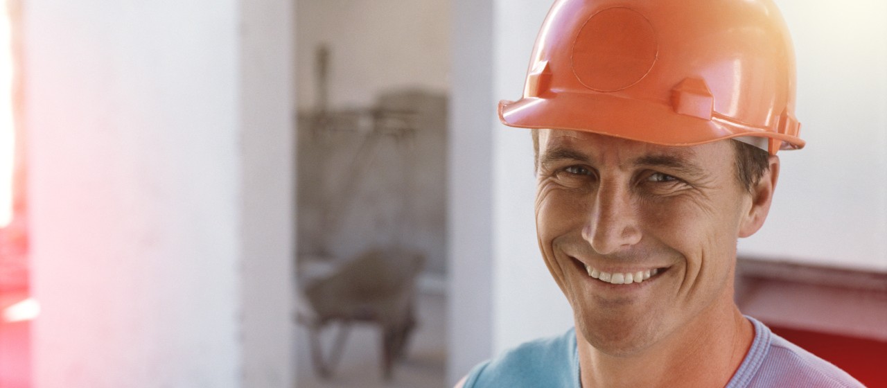 Lächelnder Bauarbeiter mit orangenem Bauhelm